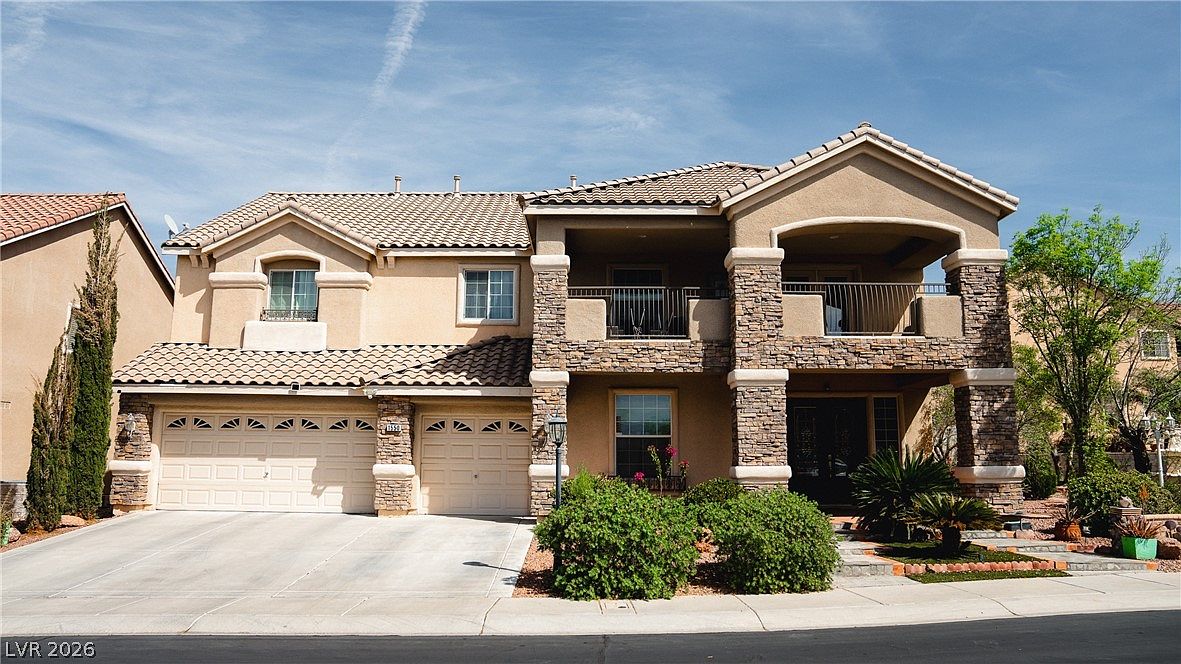 Front elevation of 1550 Via Cassia, a two-story Mediterranean home with stacked-stone columns and a tile roof in Seven Hills, Henderson